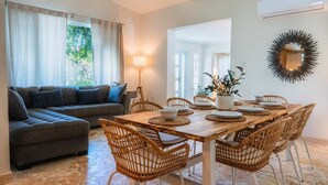 A dining area with a wooden table set for six, surrounded by wicker chairs.