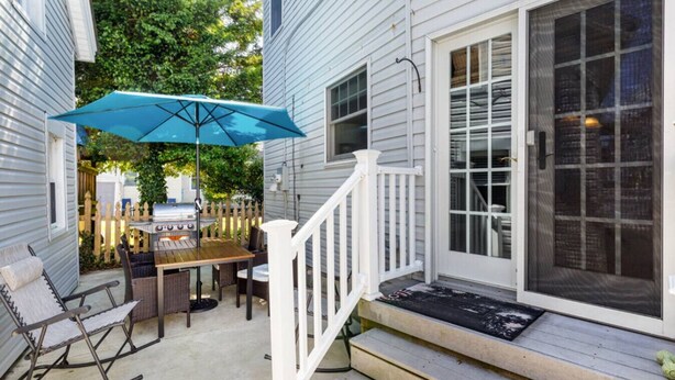 Een terras met een tafel, stoelen, een barbecue en een blauwe parasol.