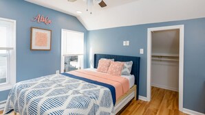 Een slaapkamer met een bed, plafondventilator, raam en kast.