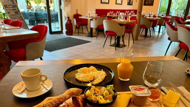 A breakfast tray with croissants, a fruit salad, cheese, and juice in a restaurant setting. - LE BON DUC (Les Billaux)
