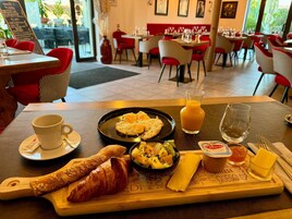 Bandeja de desayuno con cruasanes, ensalada de frutas, queso y jugo en un restaurante.