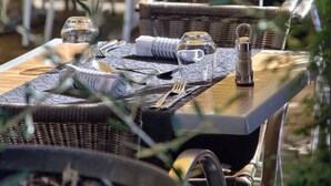 An outdoor dining area with wicker furniture, clear glassware, and metal cutlery. - LE BON DUC (Les Billaux)