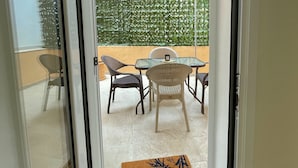 A sliding glass door leading to an outdoor patio with a table and chairs, a decorative wall, and a doormat. - Pistachio Suite - Town Centre (Corfu)