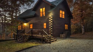 Une cabane en rondins dotée d’une véranda, d’un escalier et offrant une vue sur le ciel nocturne.