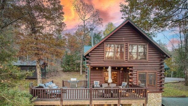 Une cabane en rondins dotée d’une terrasse, d’un espace salon extérieur et d’un jacuzzi.