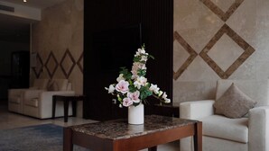 Un vestíbulo moderno con una mesa de centro de mármol, un sofá blanco y un arreglo floral en un jarrón blanco.