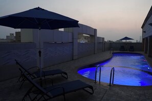 A rooftop pool area with lounge chairs and umbrellas, surrounded by modern architecture. - Moments Hotel  (Jeddah)
