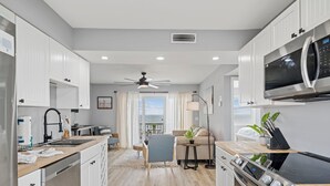 A modern kitchen with white cabinetry, a built-in microwave, and a stainless steel stove. - A Little Shore Thing- 1 Bed Oceanfront Condo (Carolina Beach)