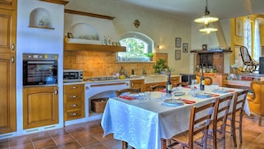Une cuisine avec des meubles en bois, un four encastré, une cuisinière à gaz et un coin repas aménagé pour prendre un repas.