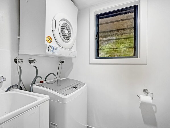 A laundry area with a washing machine, dryer, and a window with a view.