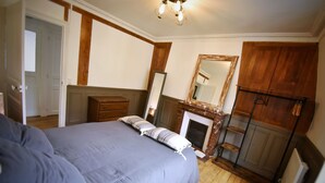 A bedroom with a bed, dresser, mirror, and wooden wardrobe.