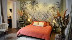 Une chambre avec un grand lit, une table de chevet, une chaise, une lampe et une fresque murale.