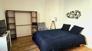 A bedroom with a bed, a desk, a chair, and a lamp.