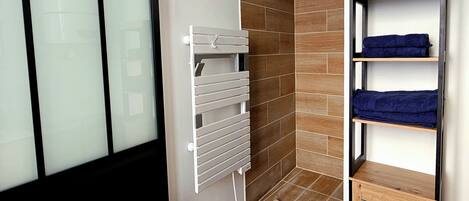 Un baño con piso de madera, un perchero, un estante con toallas y una ventana con vidrio esmerilado.