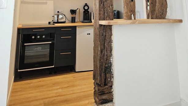 A kitchen with a rustic wooden beam structure, modern appliances, and a minimalist design.