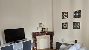 A modern living room with a sectional sofa, a flat-screen TV, a white coffee table, and a fireplace.