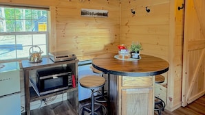 A compact kitchen with a microwave, kettle, and a small island with stools.
