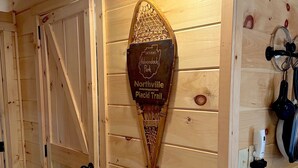 A wooden interior with a wall-mounted sign indicating the entrance to Adirondack Park and the Placid Trail in Northville.