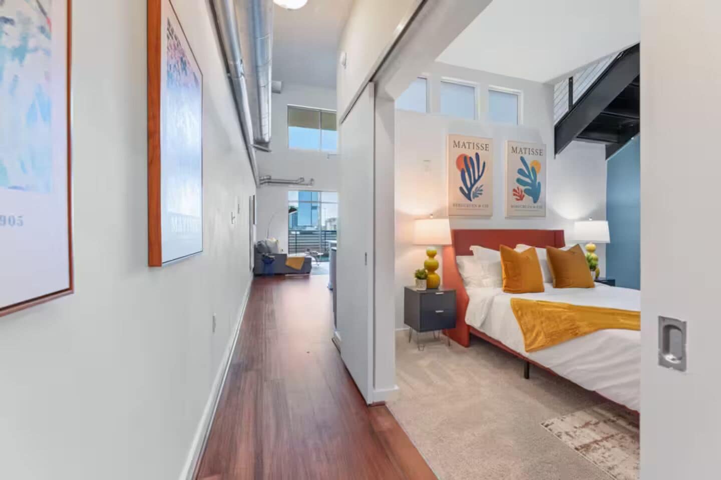 A modern hotel room with a large bed, a nightstand, and artwork on the walls.