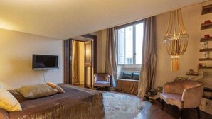 Een hotelkamer met een groot bed, een stoel, een televisie en een raam met gordijnen.