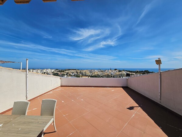 Enjoy the breathtaking view of the coastal town from this rooftop terrace, featuring a table and two chairs.