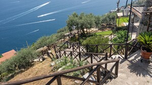 A coastal view with a wooden staircase leading down to a grassy area, overlooking the sea. - Tenuta dell'AlMa (Amalfi)