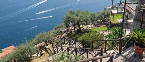 Une vue sur la côte, avec un escalier en bois descendant vers une zone herbeuse, d’où l’on peut admirer la mer.