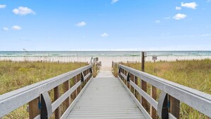 A wooden boardwalk leading to a beach with a clear sky. - Seachase 704w (Orange Beach)