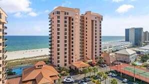A high-rise hotel with a pool, beach view, and parking area. - Seachase 704w (Orange Beach)