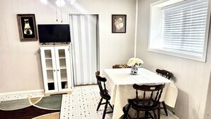 A dining area with a table, chairs, a TV, and a cabinet.