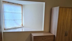 Una habitación con ventana, un armario de madera y una puerta.