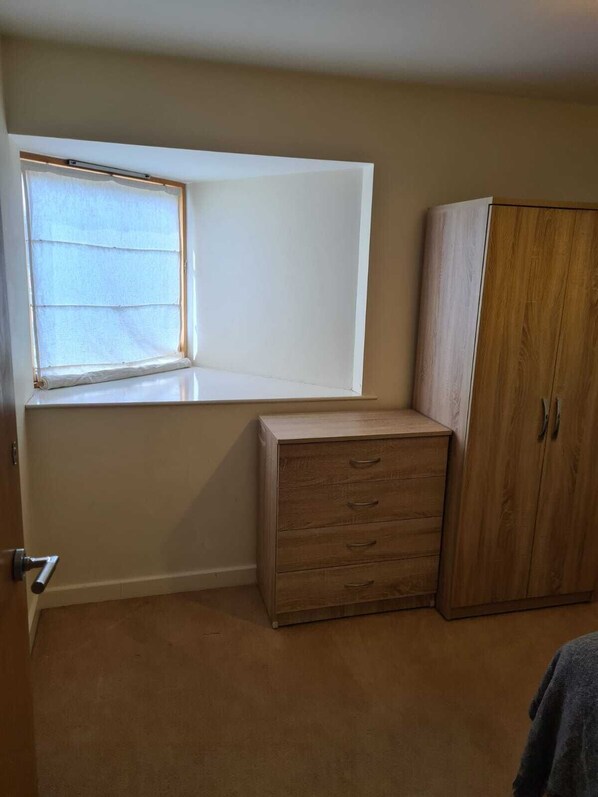 A room with a window, a wooden cabinet, and a door.