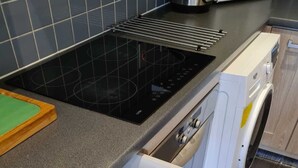 Una cocina con lavavajillas integrado, placa de inducción negra y organizador de cajones con utensilios.