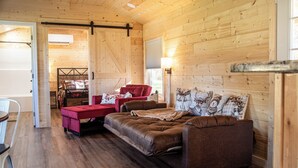 Een gezellige kamer met een bruine bank, een rode stoel en een houten vloer.
