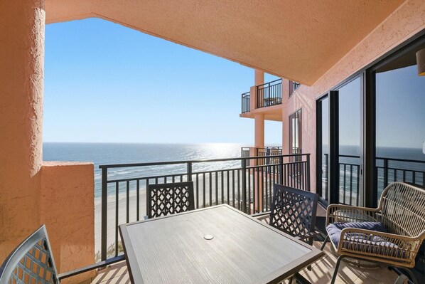 A balcony with a table and chairs, overlooking the ocean. - Seachase 1102w (Orange Beach)