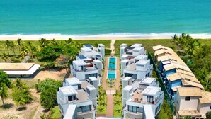 Un complexe hôtelier doté d’une architecture moderne, d’une piscine centrale et offrant une vue sur la plage.
