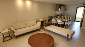 Un salon moderne comprenant un canapé, un banc, une table basse ronde et un coin repas avec des chaises et une table.