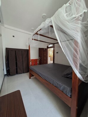 A bedroom with a canopy bed, a wardrobe, and a door leading to another room. - The Villa Sea Breeze (Thalpe)