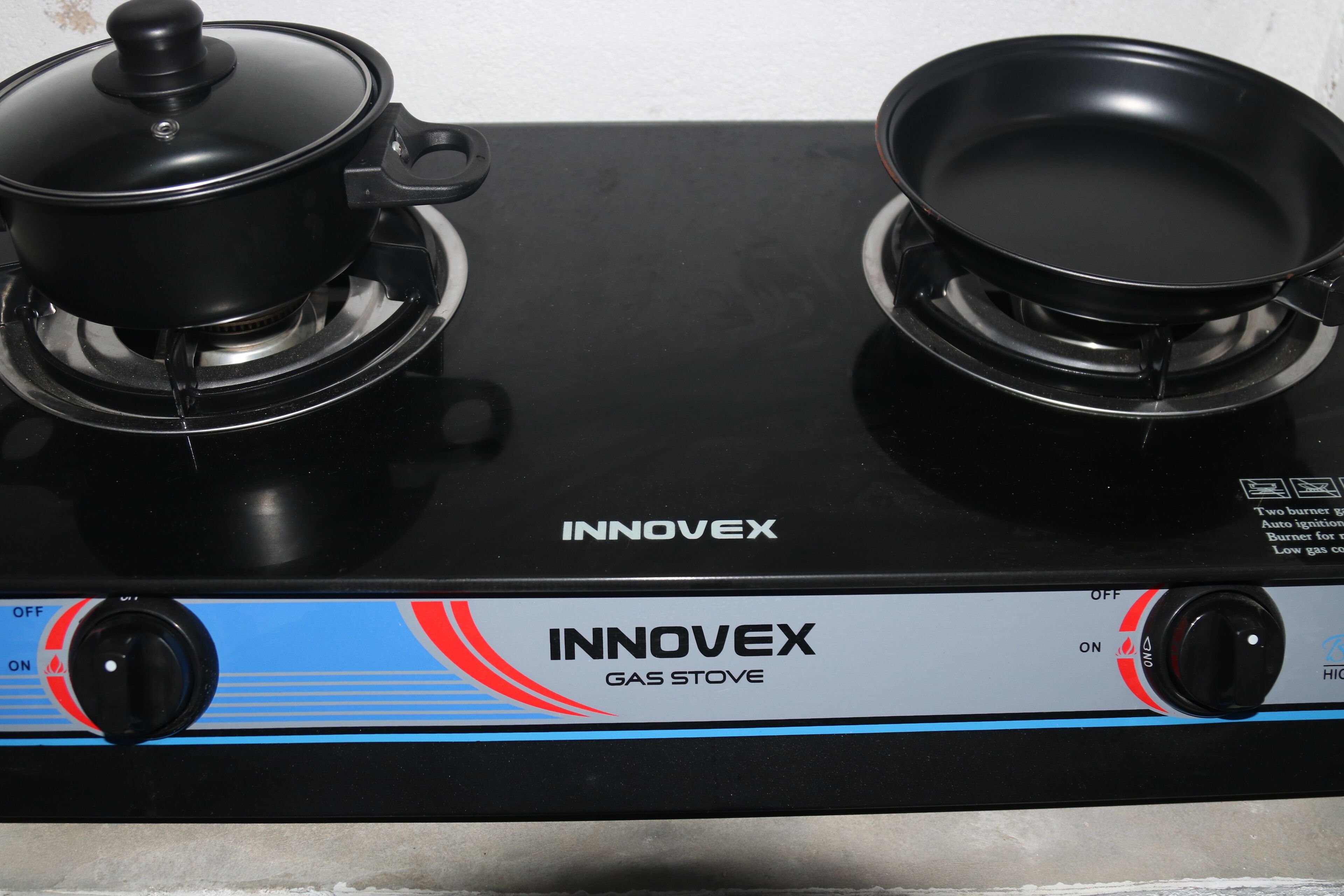 A black gas stove with two burners and a pot on the left burner.