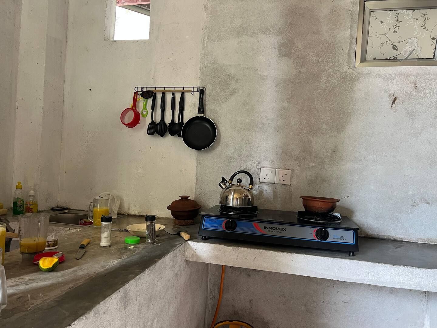 Una cocina con electrodomésticos y utensilios básicos, una estufa a gas y una ventana.