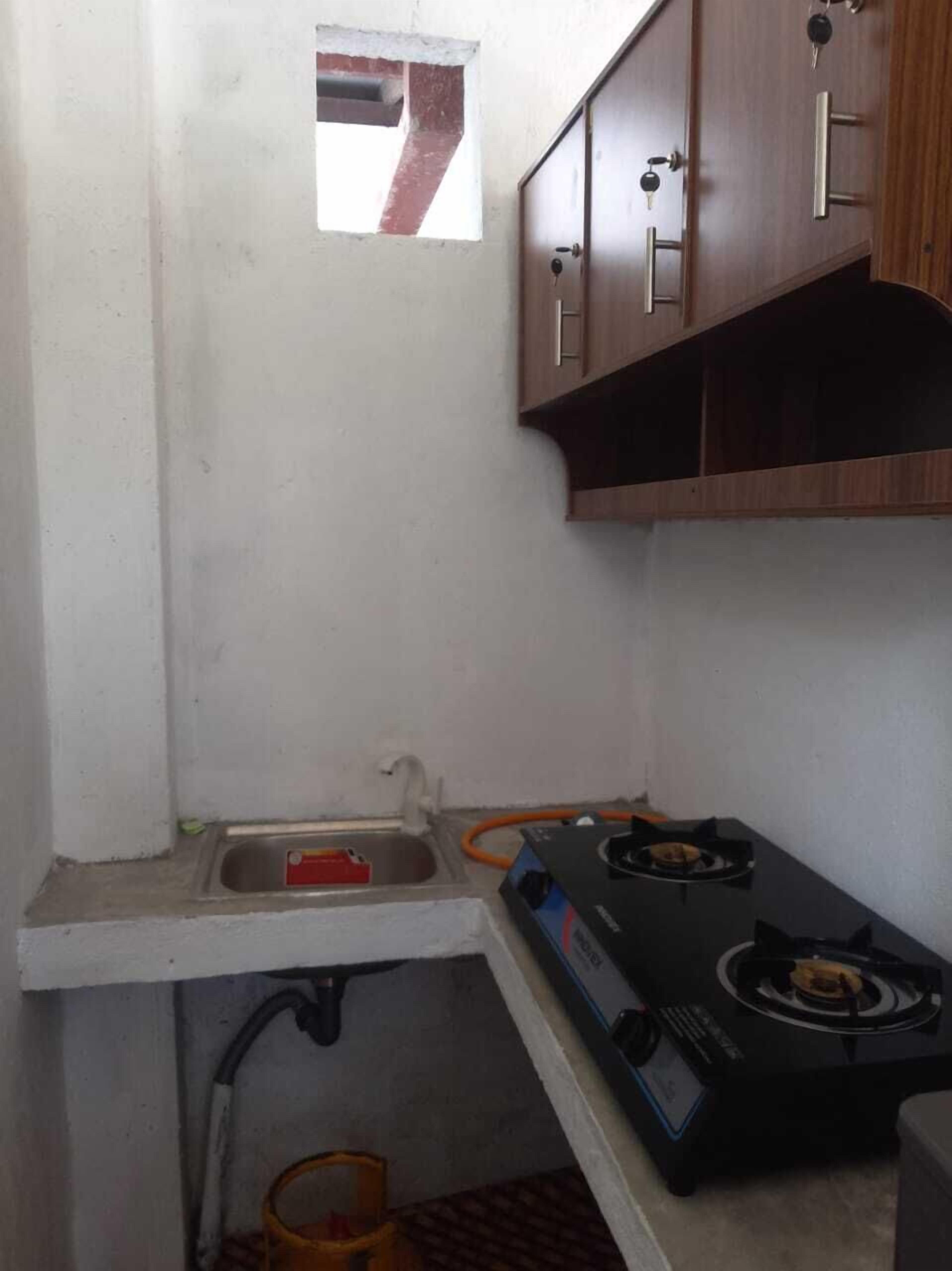 A small kitchen with a gas stove, a sink, and wooden cabinets.
