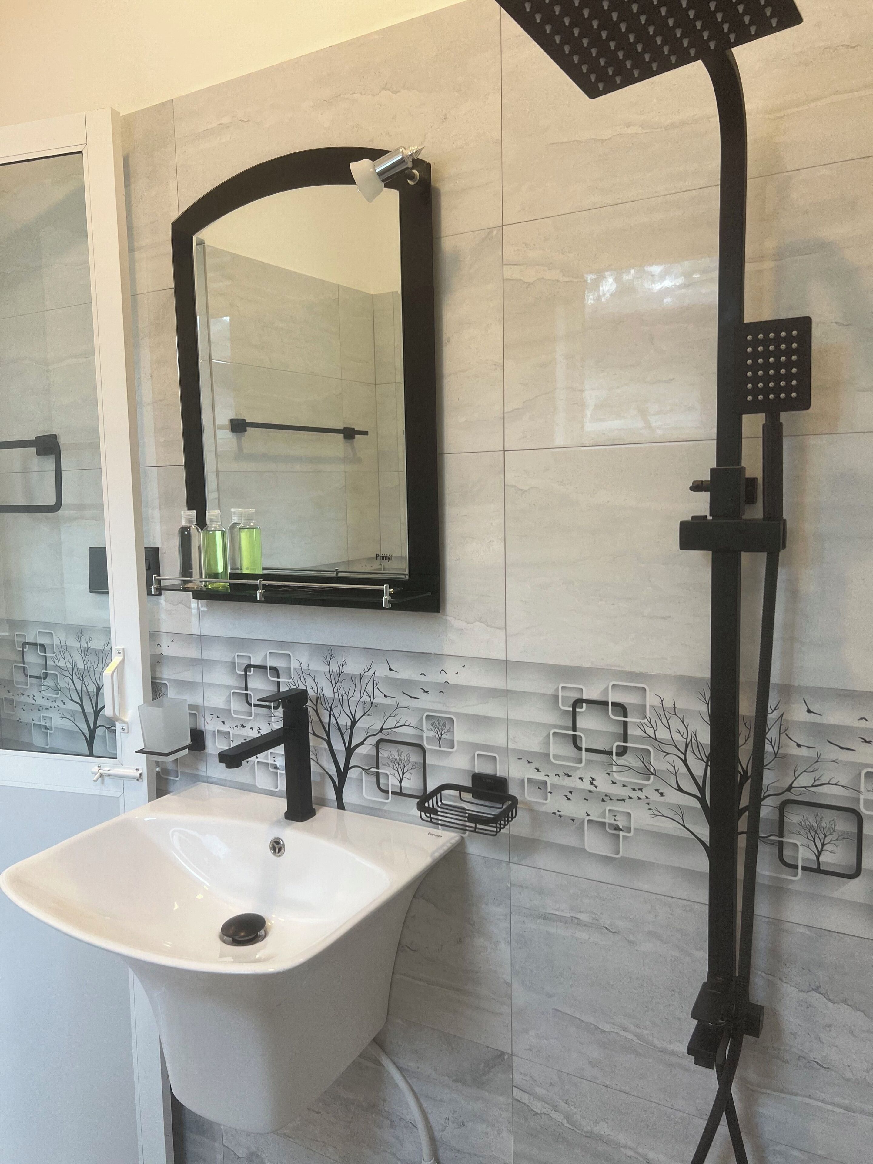 Une salle de bain avec un lavabo blanc, une pomme de douche noire et un miroir au-dessus du lavabo.