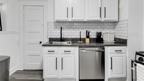 A kitchen with white cabinets, a stainless steel dishwasher, a sink, and a toaster. - Charming 2-bedroom house with AC, WiFi in wonderful Richmond (Richmond)