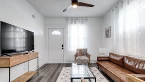 A living room with a TV, sofa, coffee table, and a ceiling fan. - Charming 2-bedroom house with AC, WiFi in wonderful Richmond (Richmond)