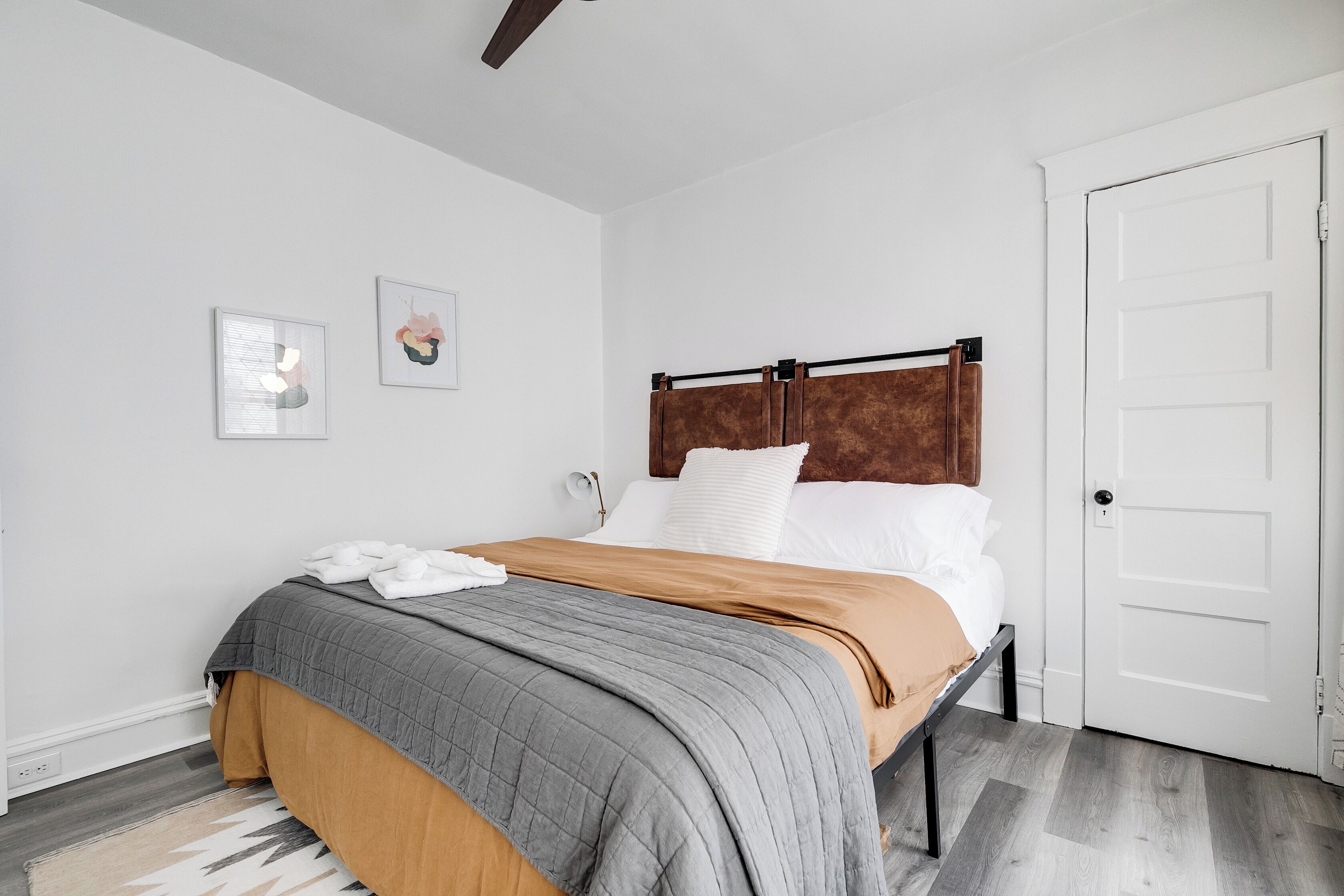 A bedroom with a bed, white walls, a wooden headboard, and a white door.