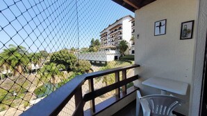 A balcony with a view of a building, a small table, and a chair.