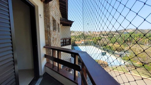 A balcony with a wooden railing overlooking a swimming pool and a landscaped area.