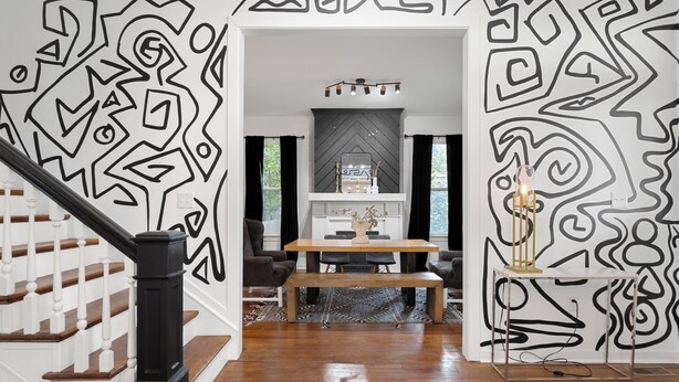 A modern interior with a staircase, a dining area with a wooden table and chairs, and a decorative wall with geometric patterns. - Spacious 4-bedroom house in charming Richmond with WiFi and AC (Richmond)