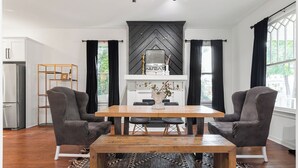 A modern dining area with a wooden table, two grey chairs, a black and white chevron-patterned wall, and a black and white patterned rug. - Spacious 4-bedroom house in charming Richmond with WiFi and AC (Richmond)