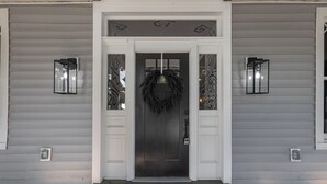 A front door with a wreath, two wall sconces, and a colorful rug. - Spacious 4-bedroom house in charming Richmond with WiFi and AC (Richmond)